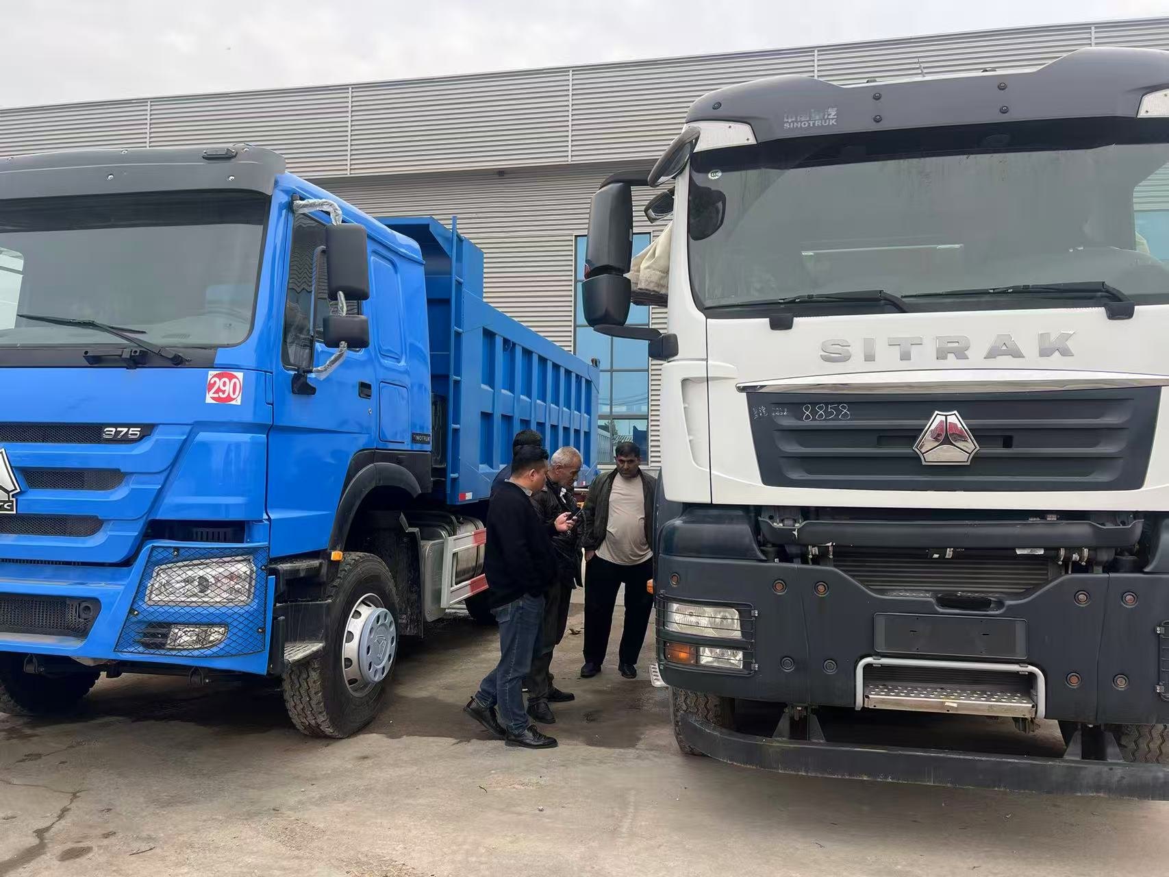 Visitors discussing commercial trucks during a vehicle-yard visit.